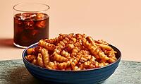 Blue bowl holds crispy, twisted snack sticks. Glass of iced drink sits beside bowl. Warm, neutral-toned background, AI generated [IBR125448905]
