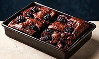 Freshly baked chocolate brownies topped with blackberries in a baking pan, AI generated [IBR125448909]