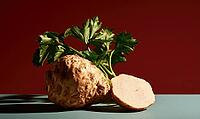 Fresh celery root with green top and cut slice. Dark red background. Smooth green surface. Natural light highlights texture, AI generated [IBR125448910]