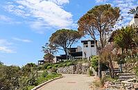 White washed villas with lush Mediterranean vegetation on a hill in Bitez, Bodrum, Turkey with a paved road [IBR125462042]