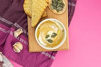 Pea soup with pumpkin seeds, next to greens and pumpkin with garlic stand on a purple towel. Top views with clear room [IBR125462072]