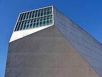 Casa da Música building featuring angular concrete walls and glass windows under a clear blue sky [IBR125462077]