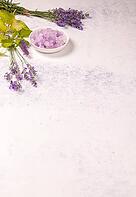 Lavender bath salts in a bowl with fresh lavender sprouts and green leaves, symbolizing natural spa treatments, aromatherapy, and wellness for relaxation [IBR125462081]