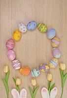 A festive arrangement of colorful Easter eggs in a circular pattern with tulip flowers, celebrating spring and holiday traditions [IBR125462105]