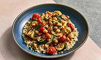 Blue plate holds quinoa, chickpeas, zucchini, and cherry tomatoes. Meal is fresh, colorful, and healthy. Plate rests on light pink and gray surface, AI generated [IBR125472262]