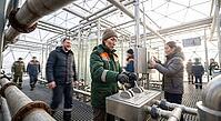 Biotechnology operators control industrial algae photobioreactors inside a geodesic greenhouse facility, managing circular food systems and hydraulics, skilled technical personnel adjust high pressure stainless steel valves alongside interactive monitor s [IBR125472263]