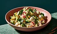 Fresh seafood salad in pink bowl on green surface. Mixed with diced cucumber, corn, and herbs. Light dressing coats ingredients evenly, AI generated [IBR125472270]