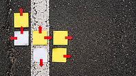 Top view of blank sticky notes with red arrow markers pointing different ways on dark asphalt beside faded white lane line, crossroads concept, studio shot, AI generated [IBR125472276]