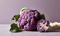 Purple cauliflower with green leaves and cut half on gray surface, AI generated [IBR125472295]