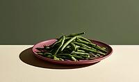 Fresh green beans on a pink plate. Plate sits on a light surface. Background is muted green. Beans appear crisp and vibrant, AI generated [IBR125472302]