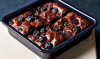 Freshly baked chocolate brownies with blueberries in pan. Rich, moist texture with visible berries on top. Dark pan sits on light countertop surface, AI generated [IBR125472307]