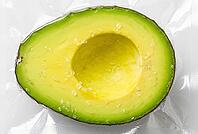 Vacuum sealed avocado half with sea salt crystals in transparent plastic packaging for food preservation, sous vide culinary preparation and freshness, high pressure processing technology shields perishable organic fruit flesh against rapid oxidation, the [IBR125472337]