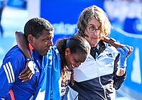 27 September 2026, Athletics: BMW Berlin Marathon 2026, from left: Tigst Assefa (ETH 2:11:04) crosses the finish line, exhausted, and is supported by a team at the 2026 BMW BERLIN MARATHON [IBR113453124]