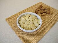 Planed almonds, almond leaves as a snack in a small porcelain bowl [IBR125492350]