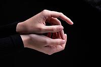 Close-up image of beautiful female hands with delicate pink manicure on nails on black background. Hand skin care, manicure and beauty treatments. Elegant and graceful hands with thin graceful fingers [IBR125492405]