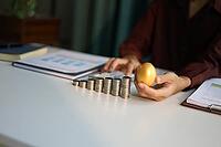 Rising stack of coins on table and golden eggs on businessman hand metaphor for financial planning and investment return [IBR125492413]