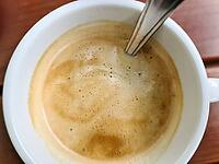 Close up view at a coffee surface in white a cup on a brown wooden background [IBR125501553]