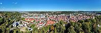 Impressive bird's-eye view of Biberach an der Riß. The photo shows the historic old town with its characteristic red roofs, traditional half-timbered houses and distinctive church towers. Nestled in a hilly, green wooded landscape, the urban area stretche [IBR125501639]