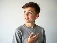 Thoughtful teenage boy gesturing with his hand on his chest while looking upwards with a smile, AI generated [IBR125502150]