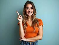Studio portrait of a cheerful young woman pointing her finger up while smiling on a blue background, AI generated [IBR125502157]