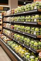 Fresh green apples sealed in transparent plastic clamshell containers line supermarket grocery store shelves, representing consumer retail logistics, pristine rows of refrigerated display racks showcase standardized agricultural fruits preserved under ste [IBR125502159]