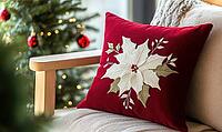 Dark red pillow with delicate white poinsettia embroidery on a light wooden bench, AI generated [IBR125502170]