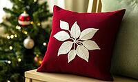 Dark red pillow with delicate white poinsettia embroidery on a light wooden bench, AI generated [IBR125502196]