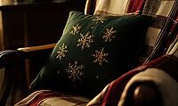 Small dark green pillow with golden snowflake embroidery on a wooden armchair, AI generated [IBR125502205]