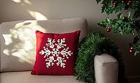 Simple red pillow with white snowflake embroidery on a light gray sofa, AI generated [IBR125502221]