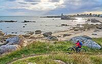 Nice senior woman cycling with her electric mountain bike at the rocky rose granite coast at Meneham site in Kerouarn, Brittany, FranceKerouarn [IBR125521079]