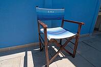 Wooden folding chair standing on blue house wall, Punta Marina, Ravenna, Emilia-Romagna, Italy [IBR125521096]