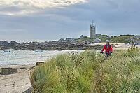 Nice senior woman cycling with her electric mountain bike at the rocky rose granite coast at Meneham site in Kerouarn, Brittany, FranceKerouarn [IBR125521106]