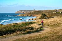 Active senior woman cycling with her electric mountain bike along the wild atlantic coast of Finisterre at Cape Frehel, Brittany, France [IBR125521114]