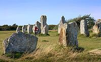 Woman cycling between the neolithic menhirs of Camaret sur mer in Brittany, France [IBR125521118]
