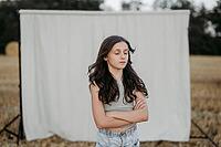 Brown-haired girl, 11, in a cornfield against a beige background [IBR125521131]