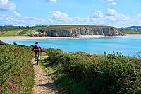 Active senior woman cycling with her electric mountain bike along the wild coast of Finisterre in southern Brittany next to Camaret-sur-Mer, France [IBR125521133]