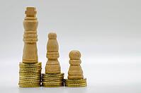 Wooden chess pawn and stacked coin arrangement on clean background isolated, representing financial strategy and value growth [IBR125527028]