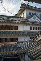 Himeji, Japan - Sep 24 2024, vertical, panoramic view from window of roofs and towers with roof tiles in courtyard of Himeji Castle, White Heron Castle, at daytime with cloudy sky, Himeji, Japan [IBR125527039]