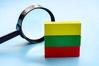 Colorful stacked wooden blocks with a magnifying glass on a wooden surface, representing learning and discovery [IBR125527042]