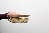 Close-up of woman taking out container with cauliflower. Hand shows glass container with lunch food brought to work [IBR125527067]