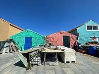 The image shows colorful fishing huts with fishing equipment in the foreground under a bright blue sky in Portugal. The photograph conveys authentic coastal life and the working world of a fishing village. Scene representing tradition, mediterranean flair [IBR125527070]