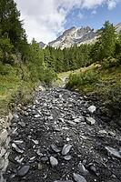Small mountain stream with more scree than water after heavy thunderstorm. Leukerbad, Valais, Switzerland [IBR125527091]