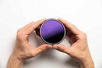 Polarizing filter for camera in male hands on a white background, close-up [IBR125527101]