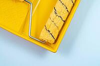 Yellow building roller for wall painting lying on a plastic tray, individual housing construction concept [IBR125527123]