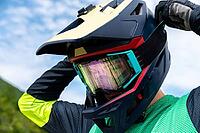 Guy adjusting motorcycle motocross helmet with goggles, close-up shot of relaxing while riding bike or dirt bike [IBR125536431]