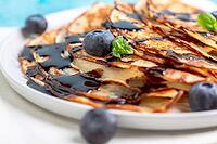 Sweet pancakes served with chocolate sauce, mint and blueberries, close-up. Selective focus [IBR125536435]
