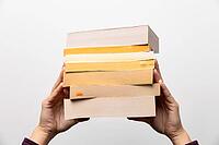 Stack of books in hand, Book Day, several books in hands on neutral white background. Home leisure. Self-isolation home, home schooling [IBR125536450]