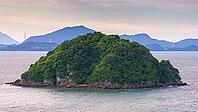 Yatsushiro, Kumamoto Pref, Japan - Oct 9 2024, panoramic aerial view of an uninhabited island covered with forest off coast of Yatsushiro, at daytime with cloudy sky, Yatsushiro, Japan [IBR125536452]