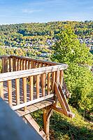 A wooden viewpoint offers a wide view of green hills and a village under a blue sky, Calw City Garden, Black Forest, Germany [IBR125536475]