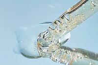 Close up of pipette with pouring liquid serum and shadows on blue background. Trendy cosmetics shot with hard shadows [IBR125557559]
